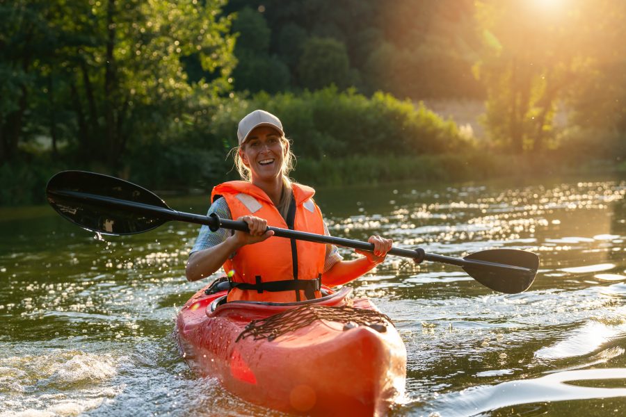 Woman,Joyfully,Paddling,A,Red,Kayak,In,A,River,During
